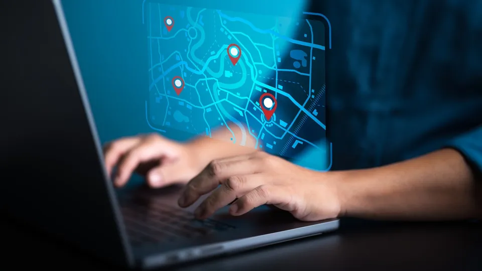 A person at a laptop with a glowing map and location pins
