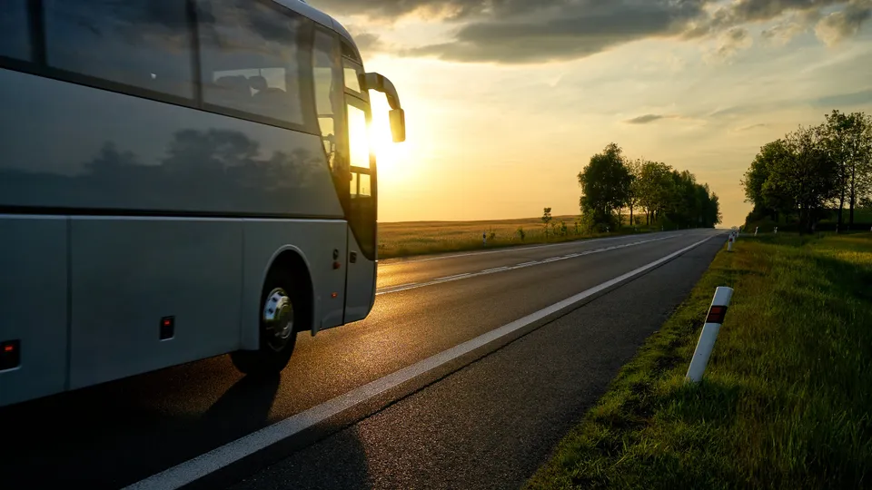 A coach on a country road at sunset