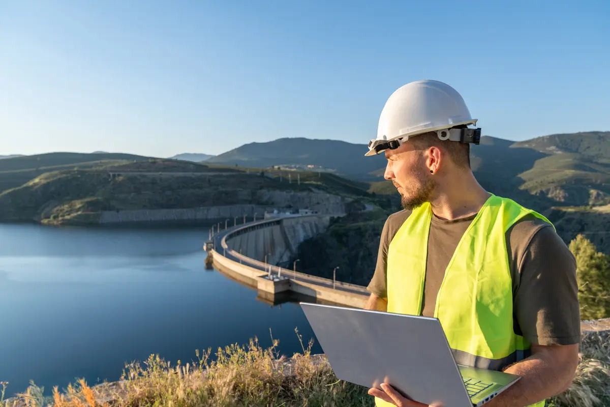 An engineer alone with a laptop at a dam