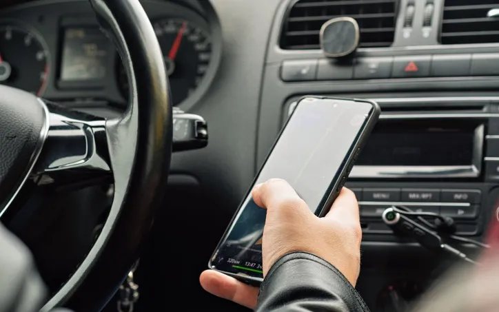 Un conducteur tient un smartphone près du tableau de bord d'une voiture
