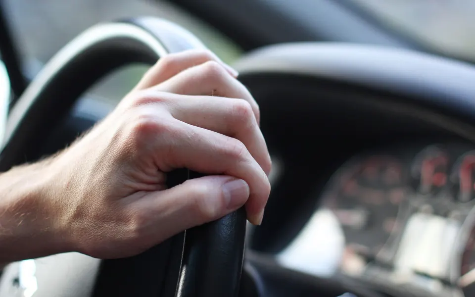 Driver's hand on the steering wheel of a company car