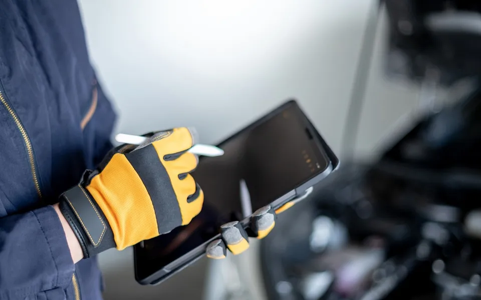 Gloved hands holding a rugged tablet